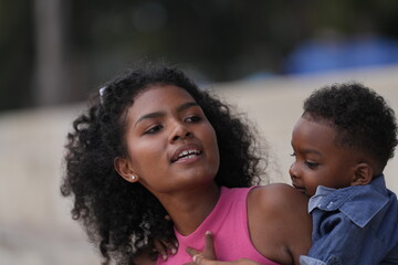 Mixed race African and Asian mother and boy is playing at the outdoor area. smiling happy family have fun running on the beach. portrait of mom and kid lifestyle with a unique hairstyle.