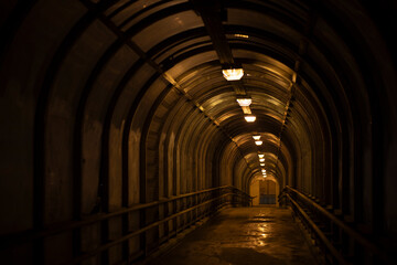 Tunnel in the dark. Pedestrian crossing through a tunnel above the road. Long corridor.