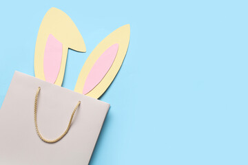 Shopping bag with paper Easter bunny ears on blue background