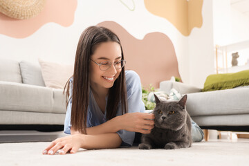Young woman with cute British Shorthair cat lying on floor at home