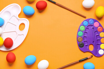 Frame made of paint palettes, Easter eggs and brushes on color background. Easter concept.