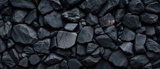 A close up of a pile of grey bedrock, resembling a road surface with a pattern of cobblestones. The rocks can be used as building material or flooring, and are depicted in monochrome photography - Powered by Adobe