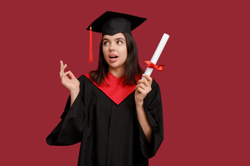 Surprised female graduating student with diploma on red background