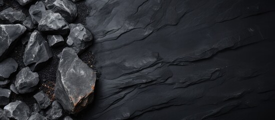 A bedrock landscape covered with a pile of black rocks, creating a monochrome photography effect. The darkness surrounds the freezing water and intrusions of wood and soil
