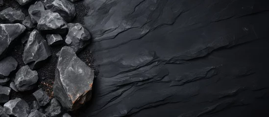 Papier Peint photo Gris 2 A bedrock landscape covered with a pile of black rocks, creating a monochrome photography effect. The darkness surrounds the freezing water and intrusions of wood and soil