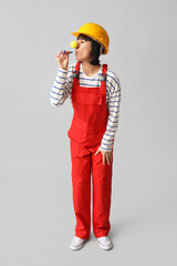 Funny young female builder with hardhat and party blower on white background. Fool's day