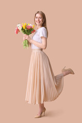 Beautiful young woman with bouquet of tulips on brown background
