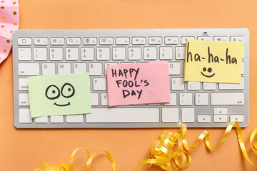 Computer keyboard and sticky notes on orange background. April Fools Day prank
