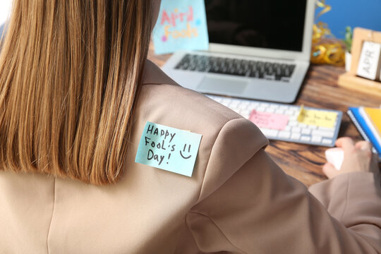 Sticky notes on back of young woman working in office. April Fools Day prank