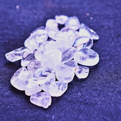 Several clear quartz gem stones or healing crystals laying on cotton fabric. 