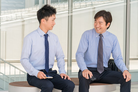オフィスの休憩所・ベンチで会話する男性ビジネスマン（上司・部下）
