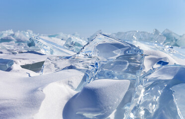 Winter natural background with fragments of blue snowy ice and heaps of pieces of ice floes on...