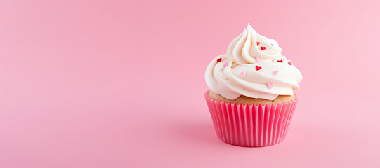 Cupcake with cream cheese frosting and sugar hearts on pink background. Valentine's day or birthday...