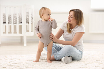 Mother with her little son on rug at home