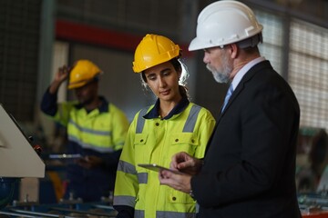 A woman worker in a yellow safety vest is talking to a foreman in a suit