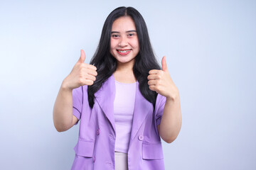 Beautiful young Asian woman with thumbs up showing ok sign isolated on grey background