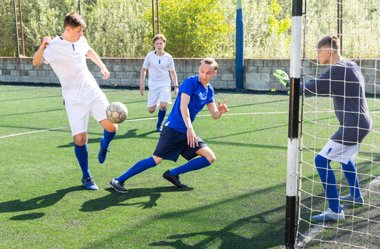 Junior football teams having golmouth scramble and struggling for ball