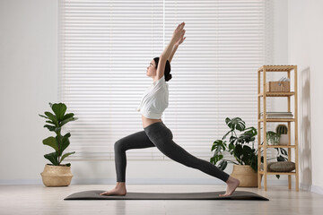 Girl practicing crescent asana on mat in yoga studio. High lunge pose