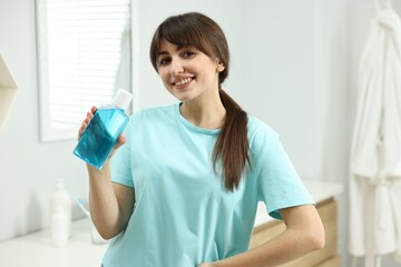 Young woman with mouthwash in bathroom. Oral hygiene