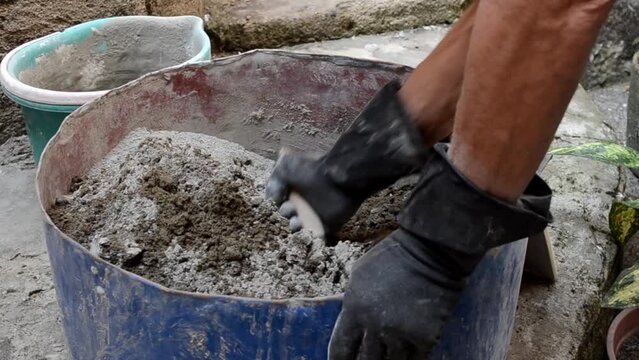 Caucasian senior adult man mixing cement and sand for construction with the help of a trowel. Walls, building, house.