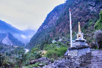 Buddhist Mantra - Om Mani Padme Hum is painted on a prayer wall and chortens dot the trail to the...