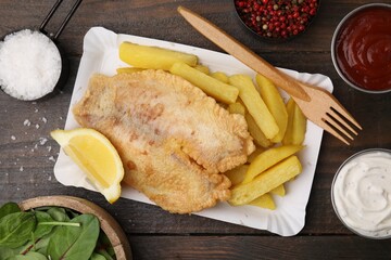 Delicious fish and chips served on wooden table, flat lay