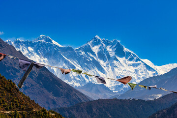 Prayer flags flutter in the breeze under the shadow of the Everest and Lhotse peaks seen from Namche Bazaar, Nepal - obrazy, fototapety, plakaty
