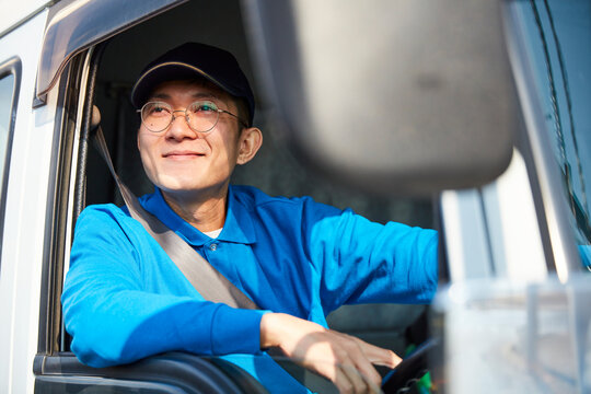 トラックを運転する作業着姿の男性