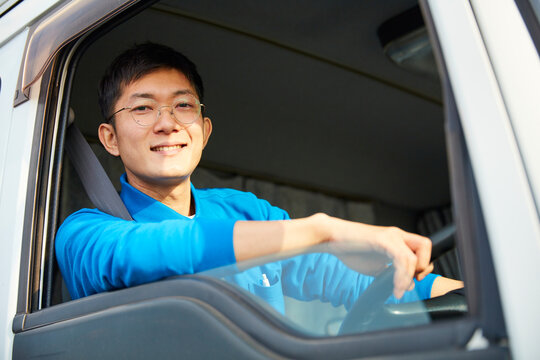 トラックを運転する作業着姿の男性