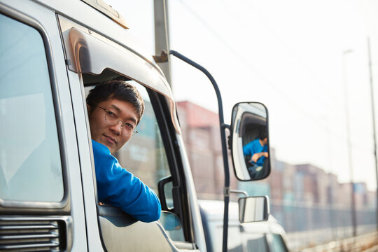 トラックを運転する作業着姿の男性