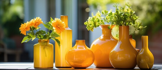 of a yellow flower in an orange bottle next to glass flowerpots and vases, representing florist garden design elements. - obrazy, fototapety, plakaty