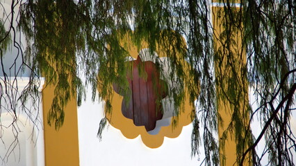 Branches of the Tule Tree hanging down in front of a window on a small, colorful church in Santa...
