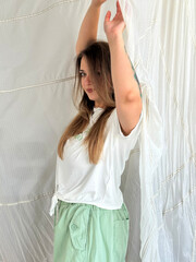 Naklejka premium Young beautiful woman with long hair and green eyes and tattoo, against the backdrop of a white parachute