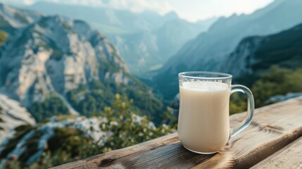 Glass jug filled with fresh milk Placed on a wooden table Against the backdrop of mountains with...