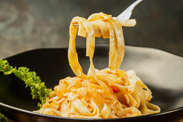 photograph of fettuccini carbonara noodles with tomato sauce garlic various seasonings in an old frying pan giving flavor to the food