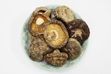 Dried shiitake mushrooms in dish plate, isolated white background