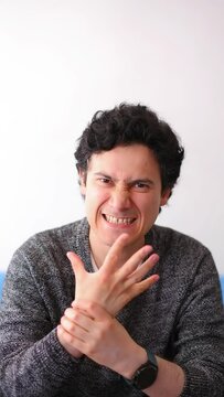 Vertical video of Latino man with messy black hair performing hand exercises to relieve severe pain