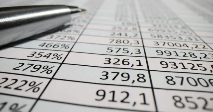 Columns with digits and metal pen on business spreadsheet