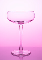 Flat champagne glass on a pink background. Empty wineglass on a colored background.