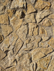 Irregular rustic stone and cement wall texture or background. Exterior wall cladding with mediterranean beige and grey stones.