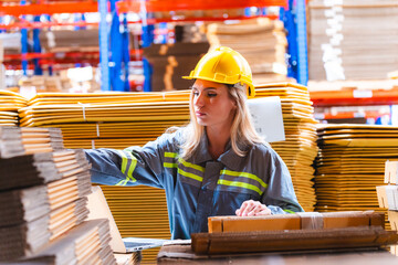 Paper and cardboard factory warehouse workers using a digital tablet while recording inventory....