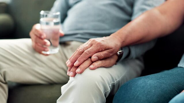 Health, holding hands and senior couple on couch together with love, comfort and support in home. Marriage, old woman and man with Parkinsons in living room with care, kindness and hope in retirement