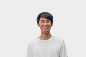 A young Asian man in his 20s wearing a white t-shirt smiling happily isolated on gray background....