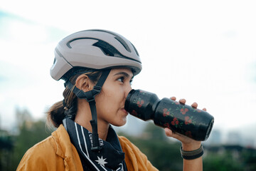 A young woman cyclist is drinking from her water bottle.
