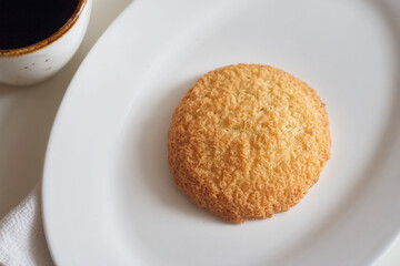 Coconut cookies in a plate and coffee on a white table
