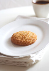 Coconut cookies in a plate and coffee on a white table