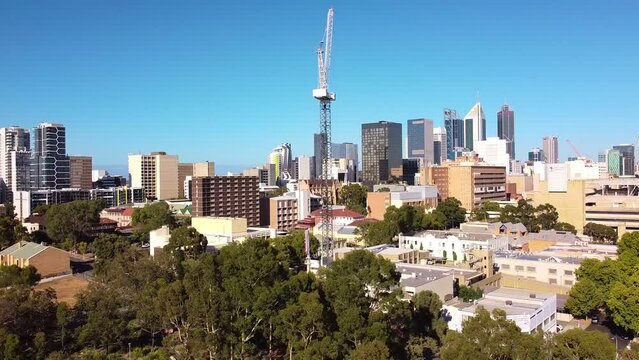 Dolly left aerial view of construction crane with Perth city buildings in the background