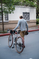 Fototapeta premium A young man walking with his gravel bike in the city.