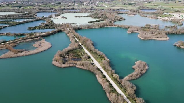 Aerial pullback above open winding body of water with pathway across reeds at ancient Antela lagoon Areeiras da Limia in Xinzo de Limia Ourense Galicia Spain