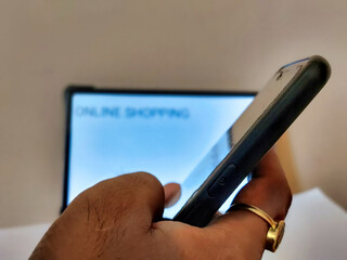 Picture of a person working on a cellphone with ONLINE SHOPPING written on a placard in blur...